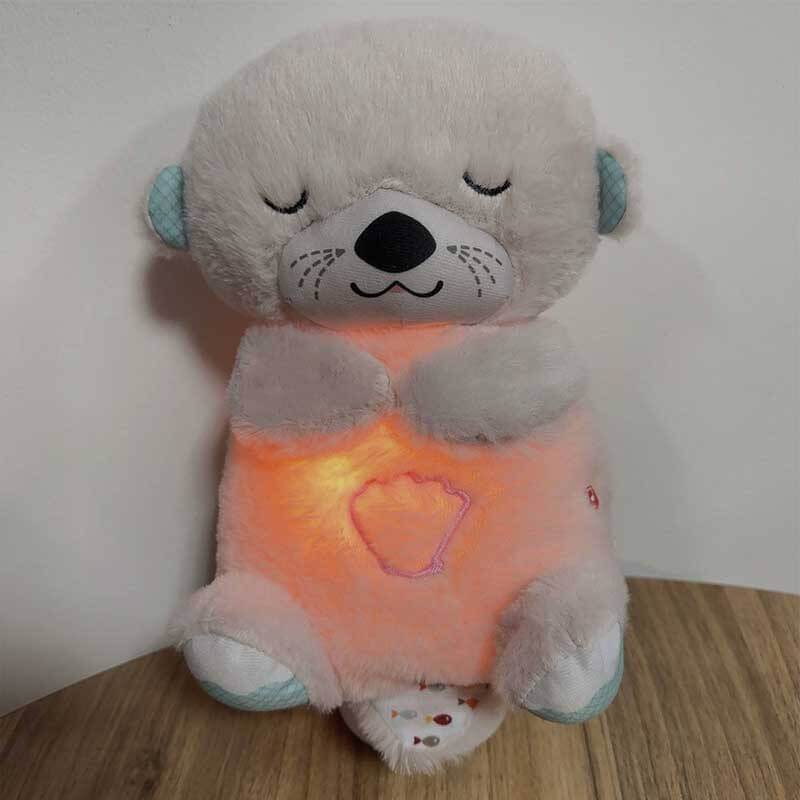 Soft baby otter plush, a sensory toy with breathing motion, next to a sleeping baby
