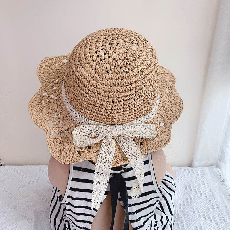 Baby straw sun protection hat with wide brim, perfect for toddlers playing outdoors in summer.