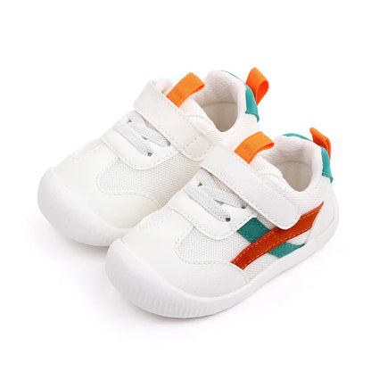 Baby's feet wearing multi-color mesh non-slip first walker shoes on a playmat