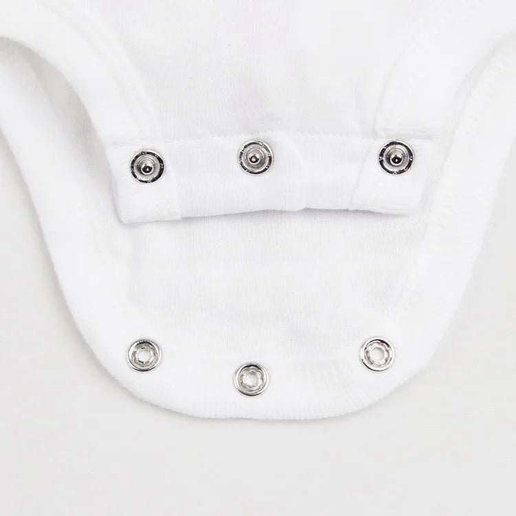 Newborn infant in a blurred background wearing a piece from the baby unisex 3-piece cotton pajama set.