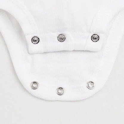 Newborn infant in a blurred background wearing a piece from the baby unisex 3-piece cotton pajama set.