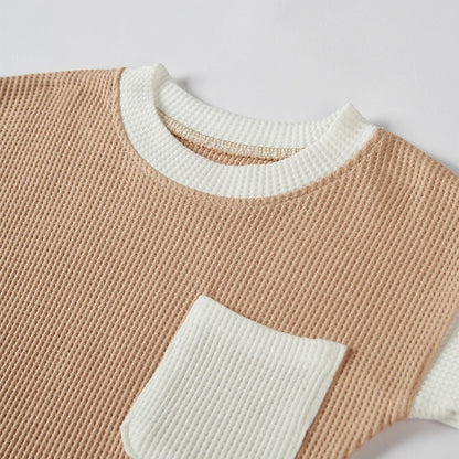 Flat lay of a short sleeve baby cotton waffle knit romper and a matching hat