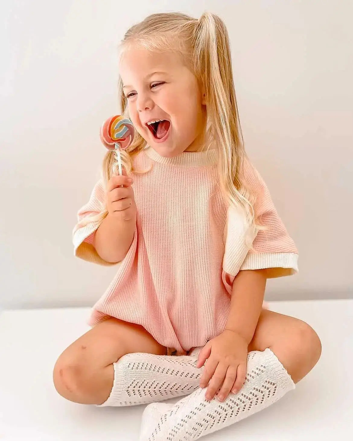 Newborn baby wearing a light-colored short sleeve cotton waffle knit romper