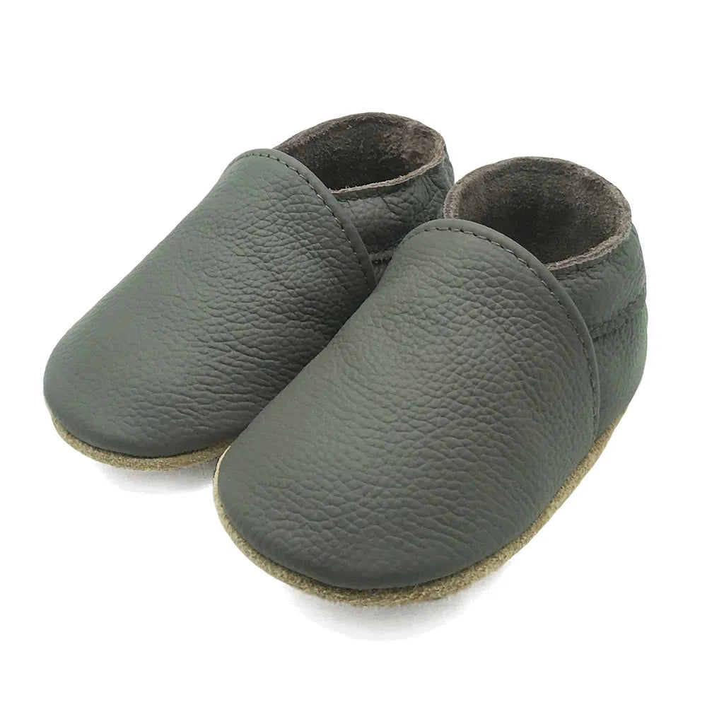Baby wearing black soft leather booties, durable and cute infant shoes for everyday