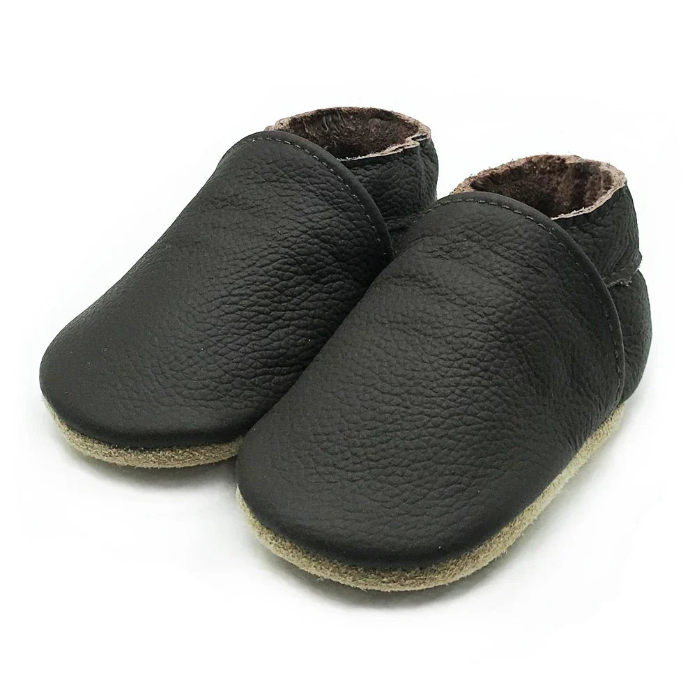Unisex black soft leather baby booties on a clean background, infant first shoes