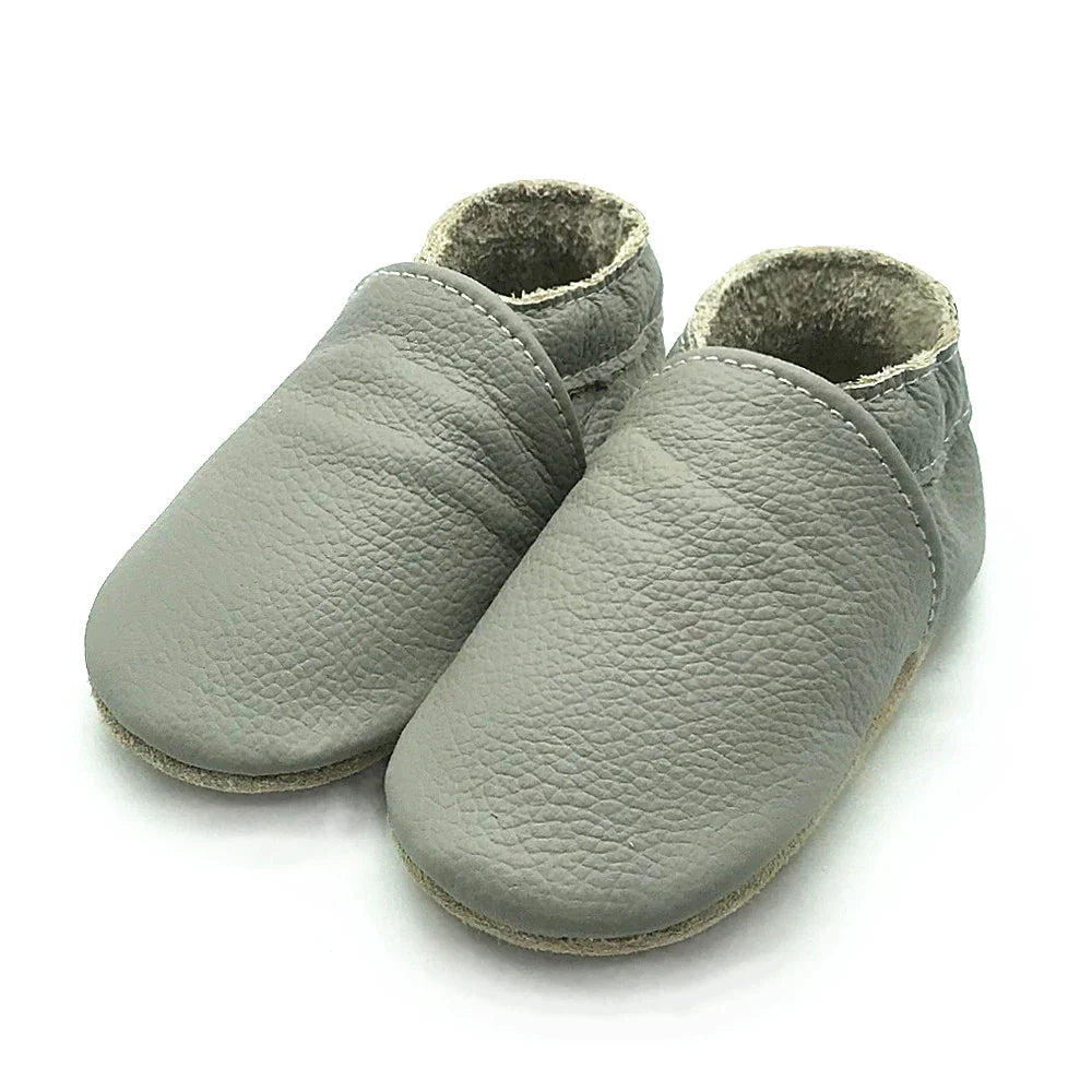 Multiple soft leather baby booties lined up, wide selection of newborn & infant shoes