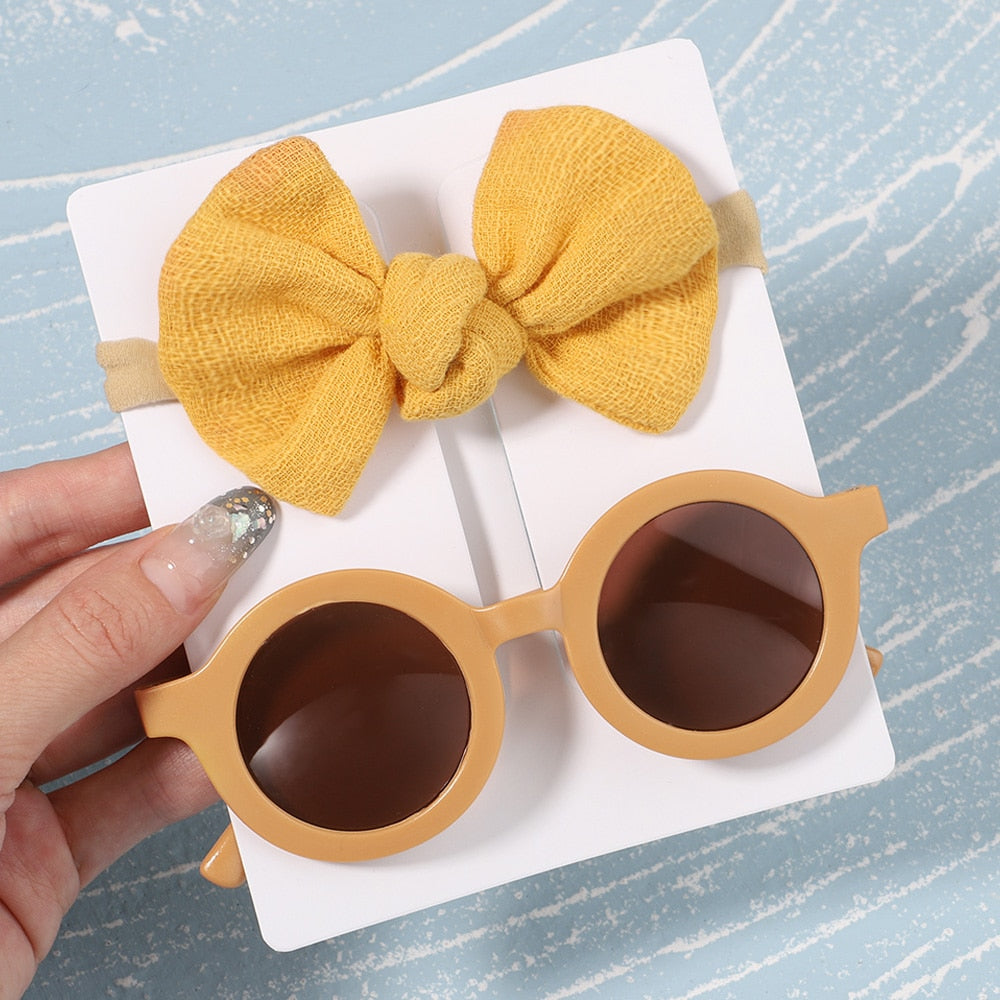 Trendy baby accessories: UV protective sunglasses & bow. Elevate infant's sun safety & look.