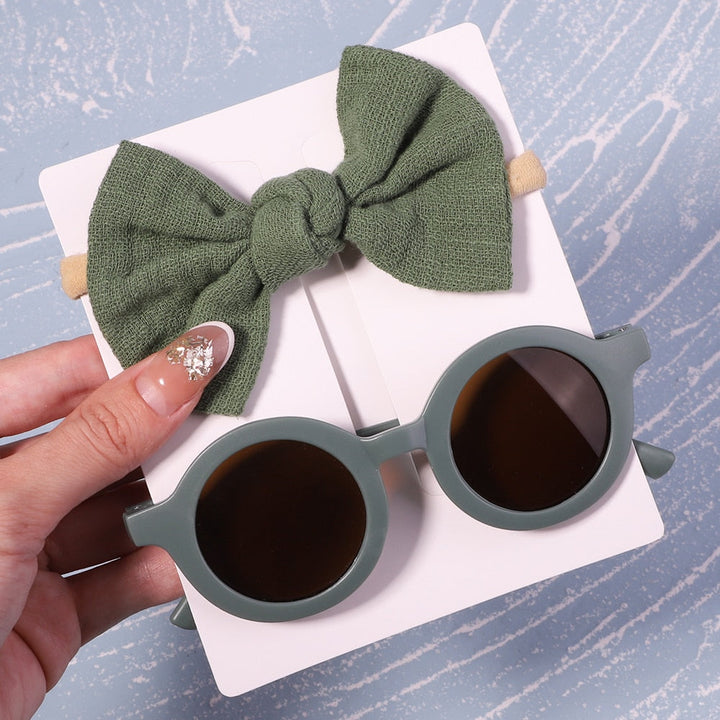 Sun-smart baby outfit addition: UV protective sunglasses & bow. Protects eyes in style.