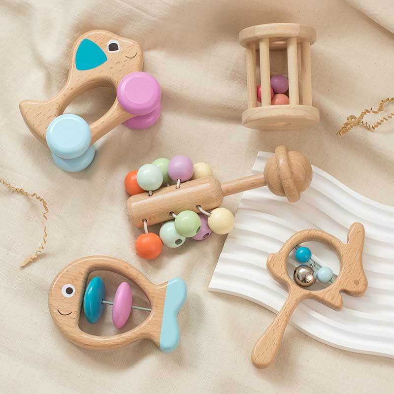 Close-up of a baby's hand holding a wooden ring teether from the toy set
