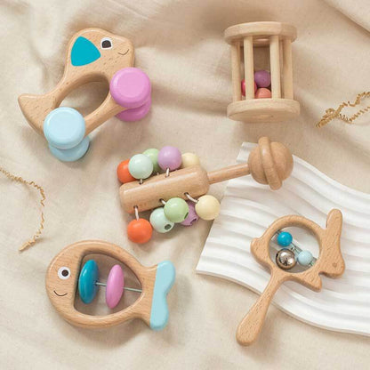 Close-up of a baby's hand holding a wooden ring teether from the toy set