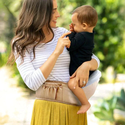 Beige ergonomic baby hip seat carrier with comfortable back support for parents, featuring a secure infant seat
