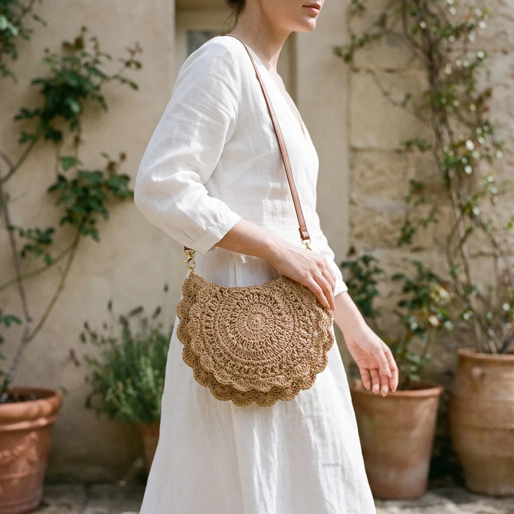 Beige textured crossbody bag for women, featuring a stylish scalloped flap and vintage-inspired saddle design.