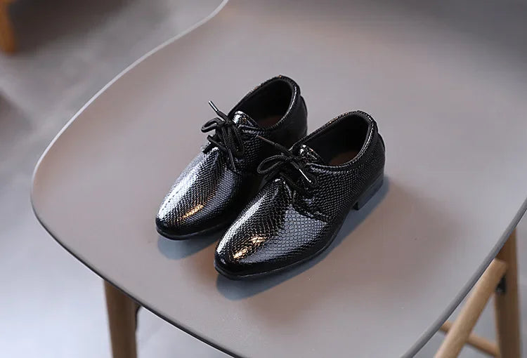 Boys' black wedding guest shoes, ensuring a polished look for young attendees.