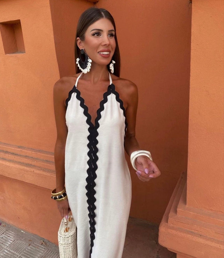 Flowing V-neck wedding guest maxi dress. Chic sleeveless design with stylish contrast trim. Great for summer parties.