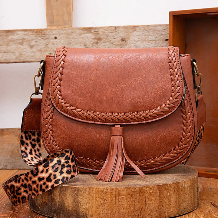Chic women's brown saddle bag with stylish tassel detail, perfect crossbody accessory for an elegant look.