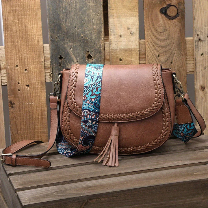 Elegant black saddle bag for women, featuring a chic tassel and adjustable crossbody shoulder strap.