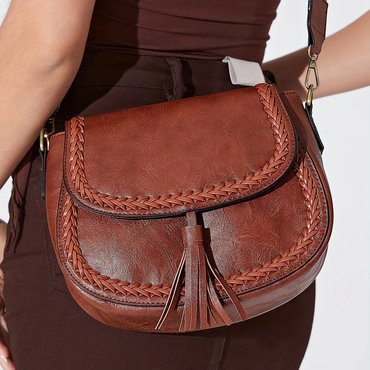 Women's brown chic saddle bag, highlighting the trendy tassel detail and smooth faux leather finish.