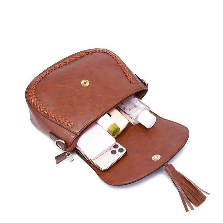 Sophisticated women's brown saddlebag with a luxurious feel, featuring a chic tassel & adjustable strap.