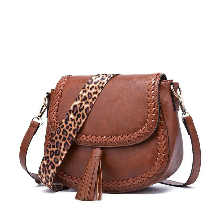 Women's chic brown saddle bag, showcasing its elegant form & stylish tassel, a perfect fashion accessory.