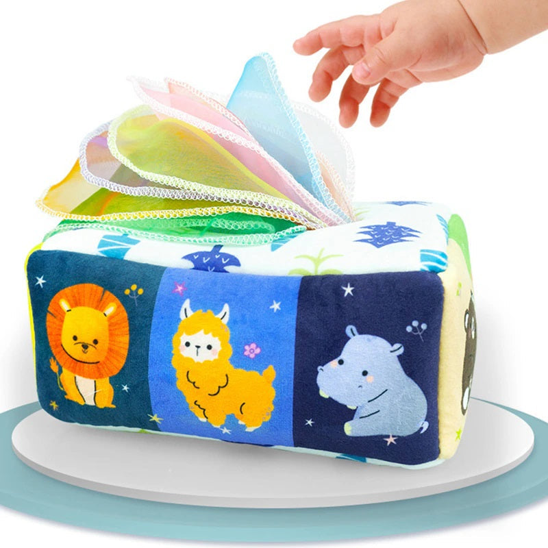 Children's soft fabric tissue box toy with colorful scarves for sensory play and hygiene learning.