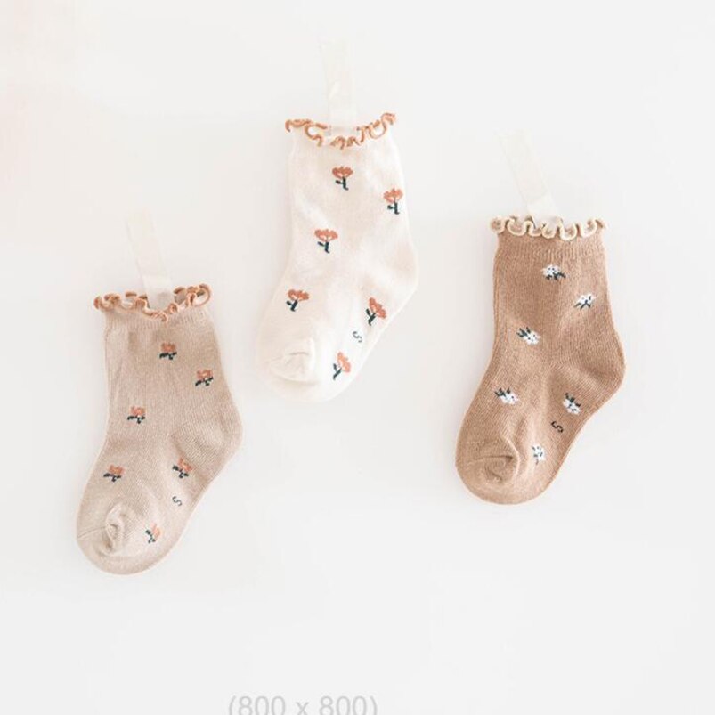 Flat lay of unisex baby ankle socks with a delicate floral pattern, perfect for all seasons.