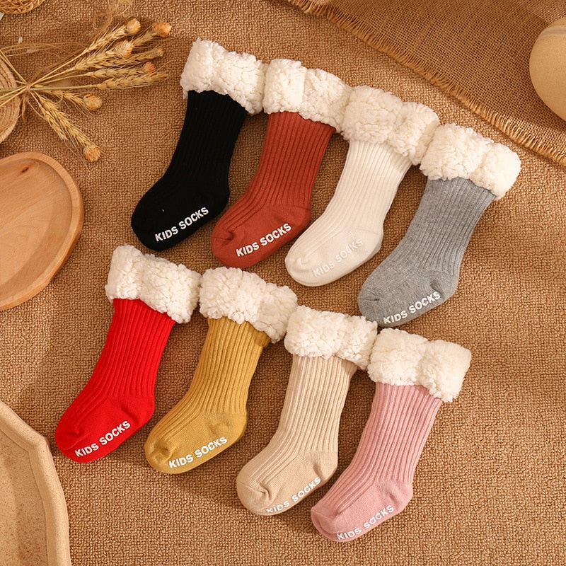 Smiling baby sitting upright, wearing thick winter socks, ensuring warmth and safety