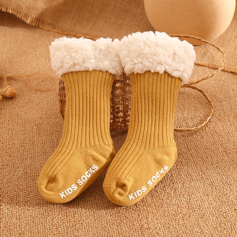 Cute baby feet wearing thick, warm cotton non-slip socks, playing safely on a mat
