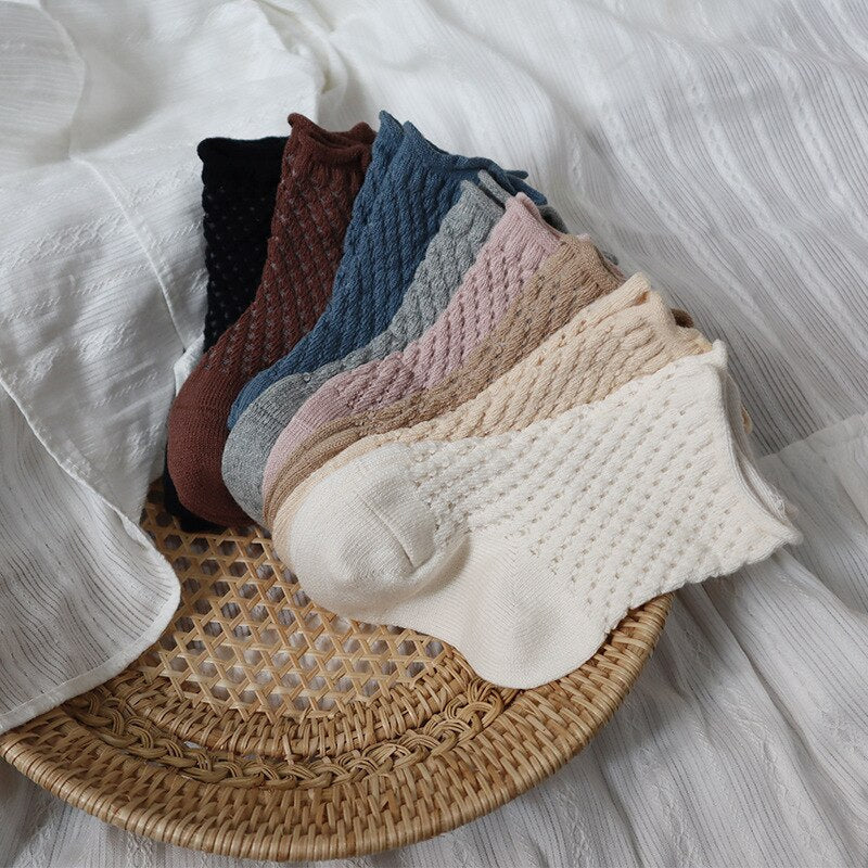 Two pairs of white and grey soft cotton mesh breathable ankle socks on a wooden surface.