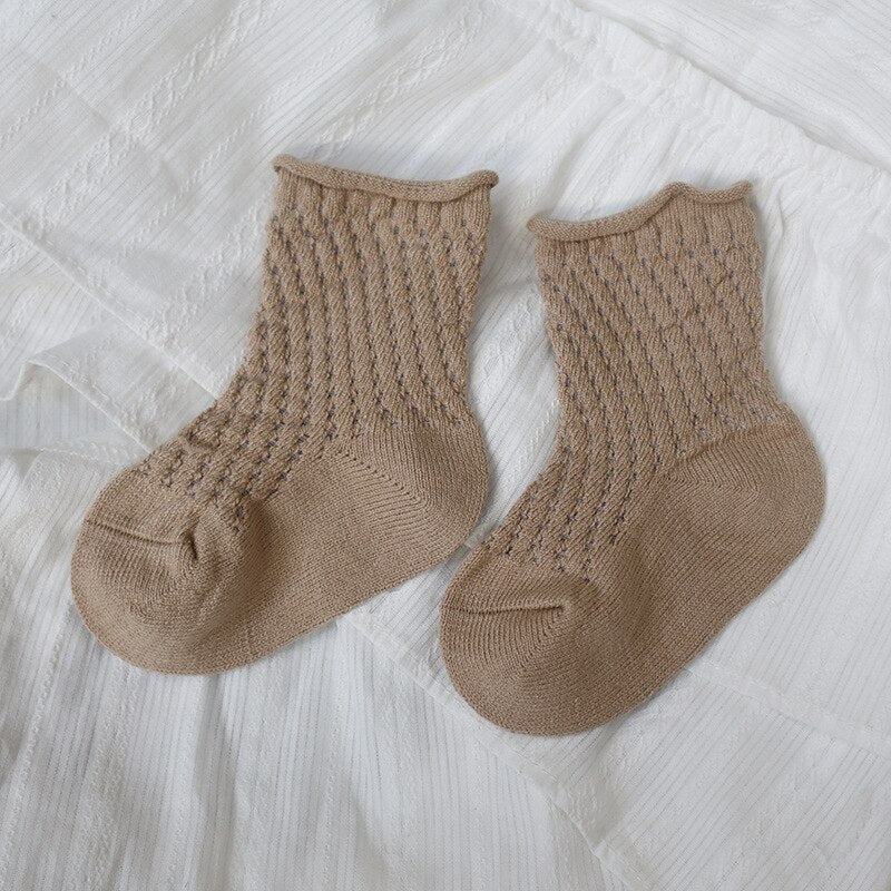 Textured detail of the mesh weave on a breathable ankle sock for children, made from soft cotton.