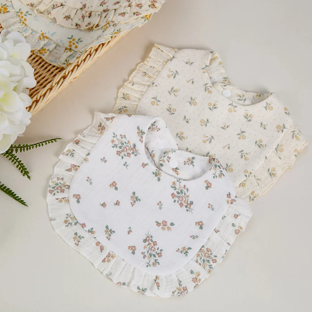 Close-up of a soft white cotton bandana bib with delicate pink floral print for infants