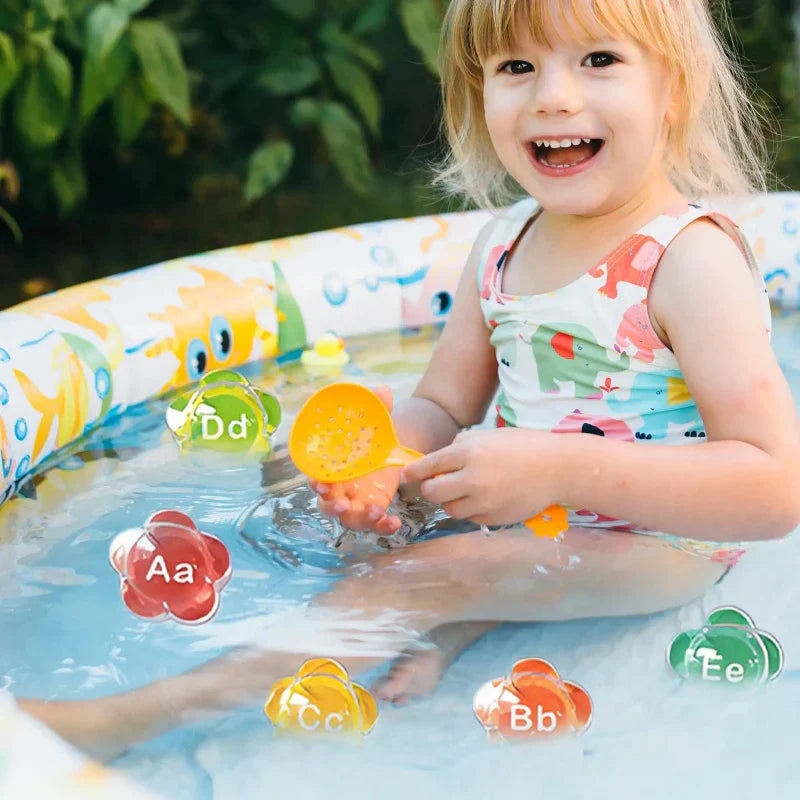 Toddler hands playing with floating alphabet letters in a bathtub, promoting sensory learning