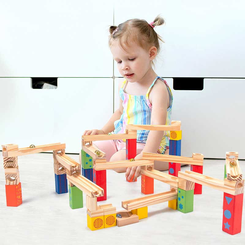 Toddler playing with wooden ball track stacking blocks toy, building a fun educational construction set