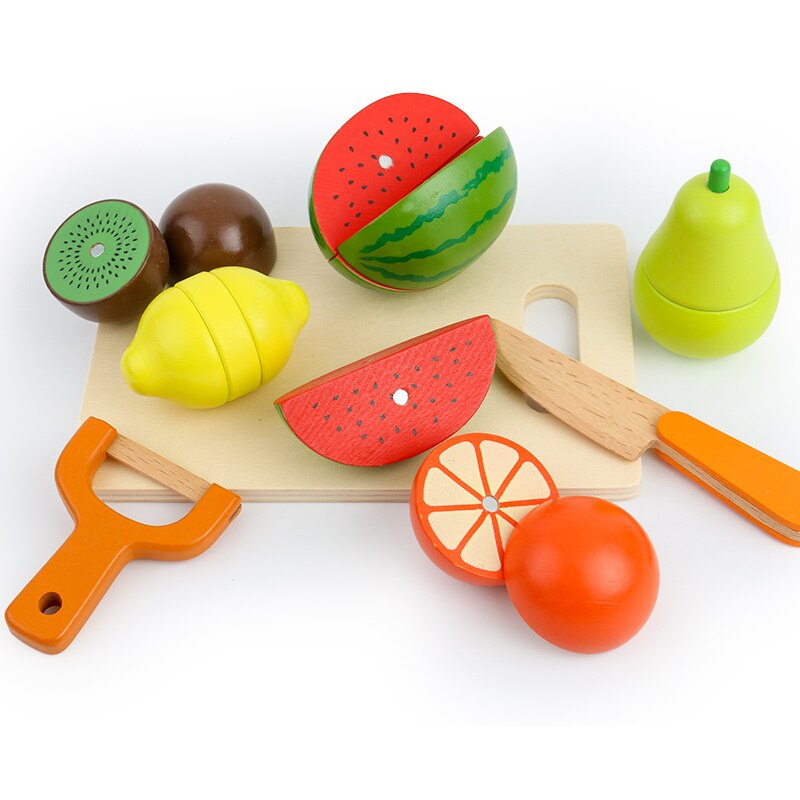 Assorted wooden play food, including fruit and vegetables, arranged on a play kitchen counter for kids