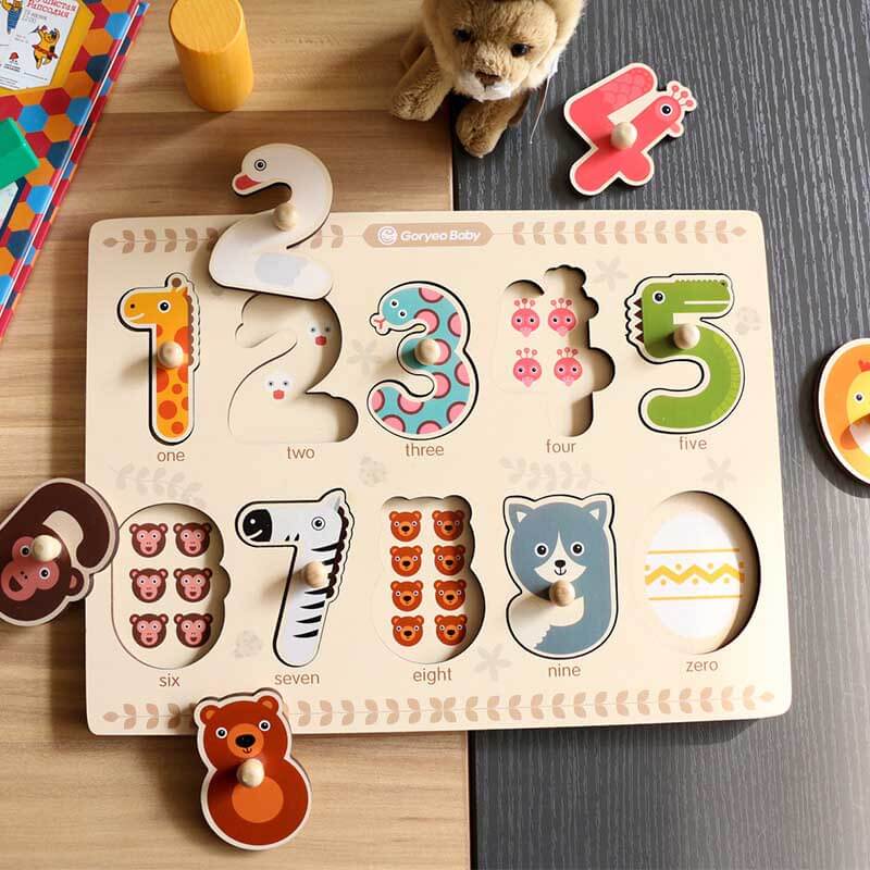 Close-up of a child's hand placing a wooden number piece into an animal puzzle board