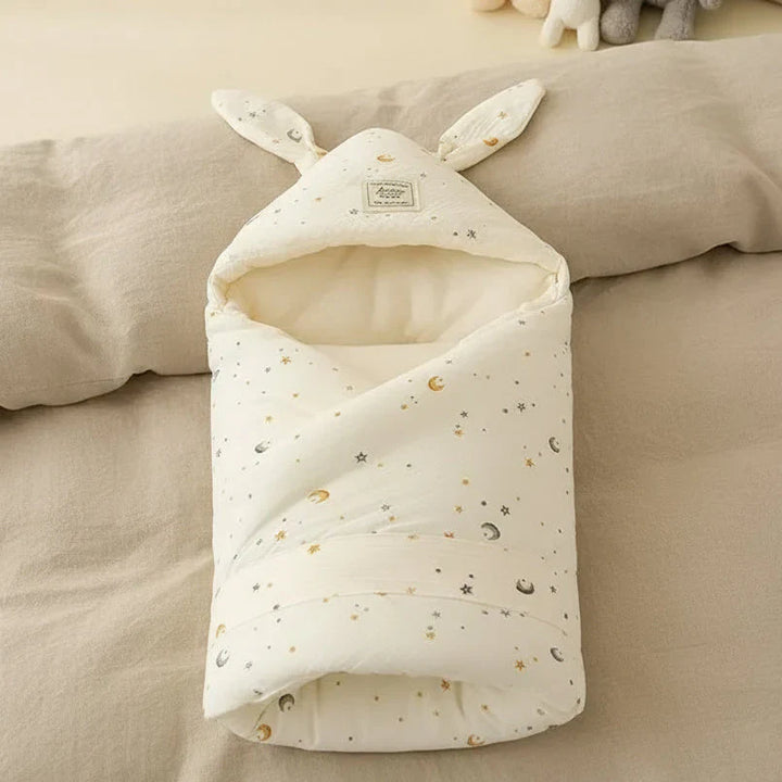A stack of folded unisex cozy swaddle blankets in various pastel colors on a wooden surface.
