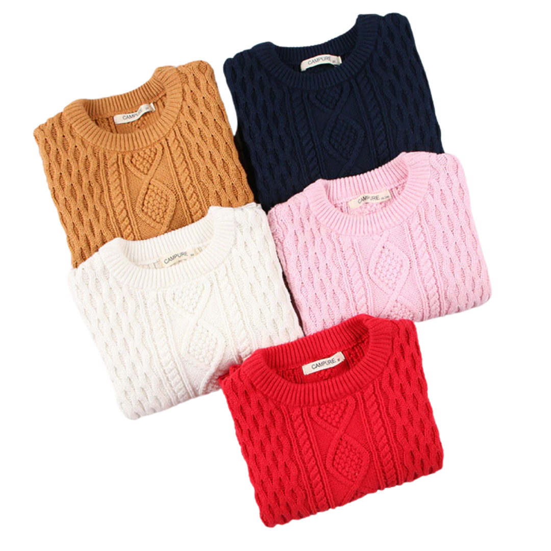 Adorable toddler wearing a thick cable knit pullover sweater, happy and bundled up for winter fashion.