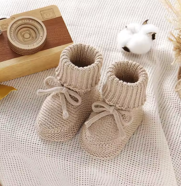 Newborn essentials: cream-colored knitted baby booties with ankle ties, gentle on skin.