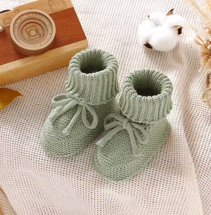 Close-up of textured knitted baby booties, showcasing soft material and delicate construction.