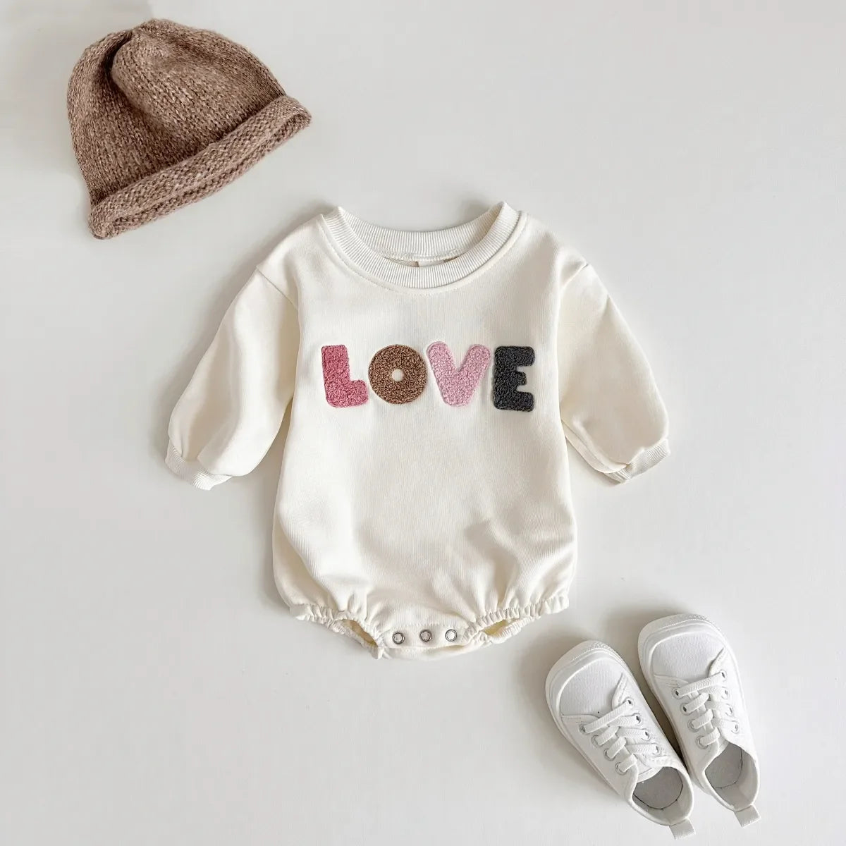 Cream baby romper with 'love' embroidery, comfortable cotton blend for newborns. Unisex infant clothing.