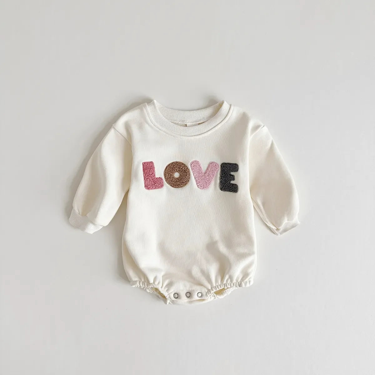 Baby girl in a cream infant romper with 'love' detail, perfect for cozy newborn fashion.