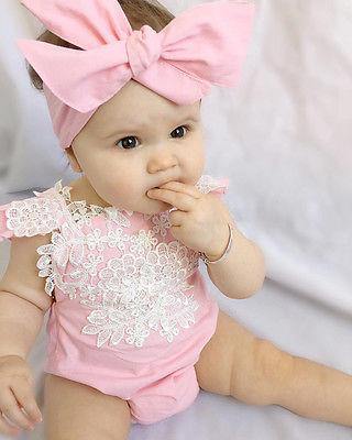 Soft pink baby romper with delicate lace detailing and a matching bow headband.