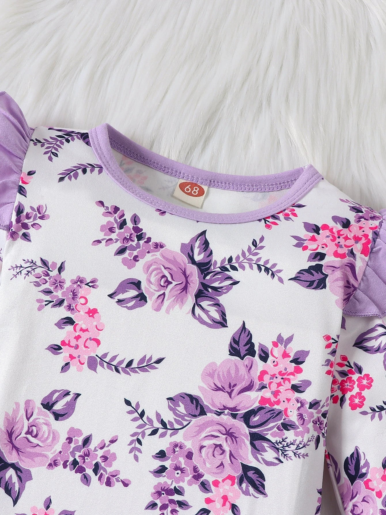 Close-up of the delicate floral print on a baby girl's long sleeve romper, soft polyester fabric.