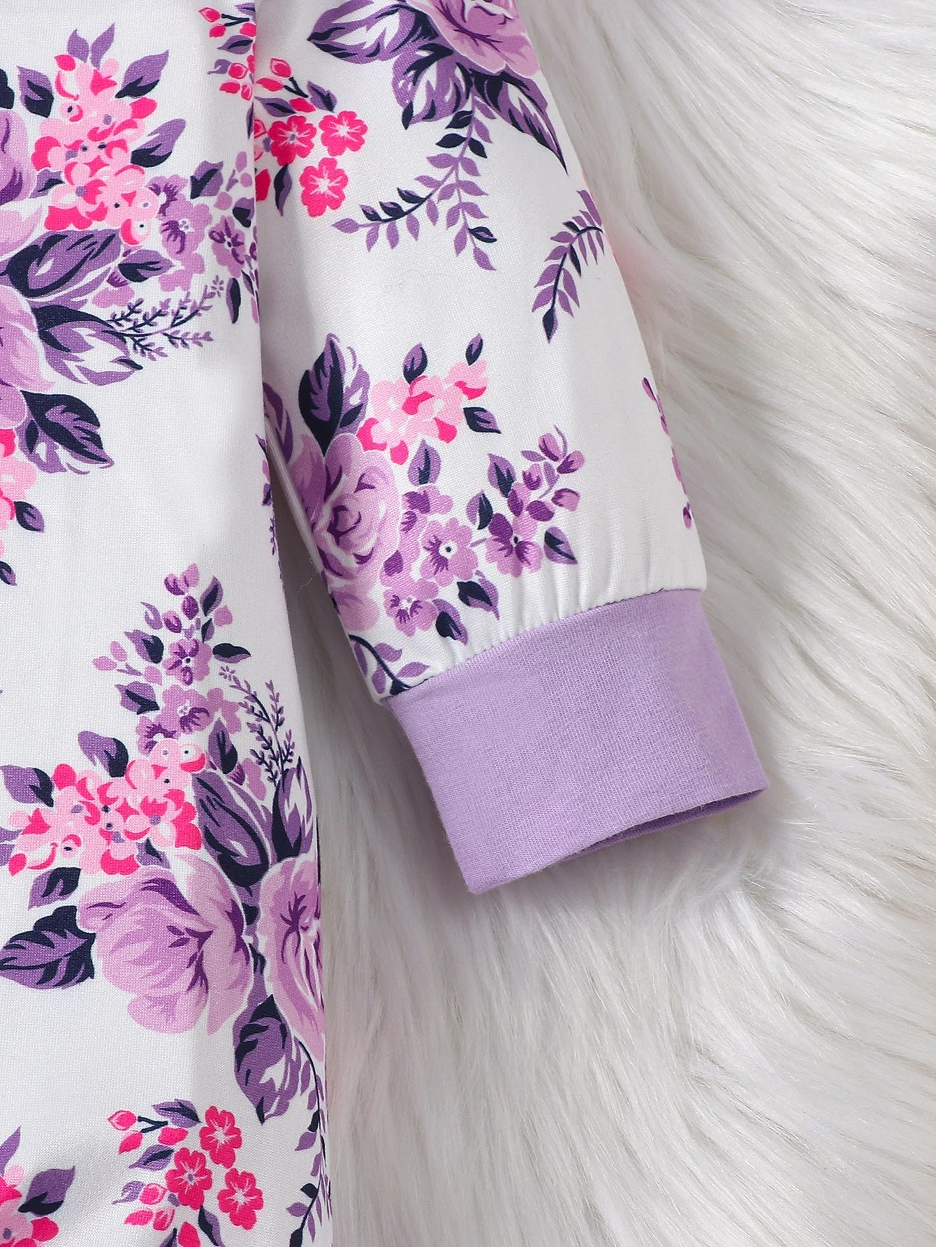 Back view of a baby's floral romper showing snap closures for easy changing, practical infant wear.