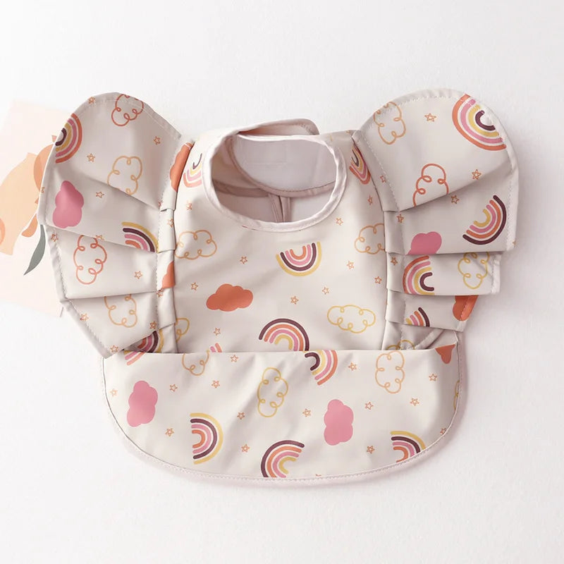 Child's hand reaching into the food catching pocket of a baby infant waterproof bib during feeding