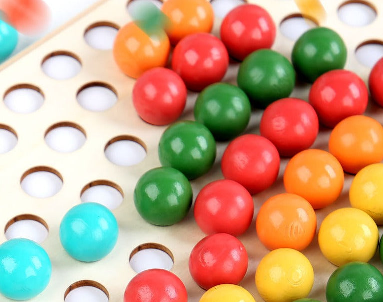 Close-up of a child's hand using tweezers to stack colorful wooden rainbow beads, boosting fine motor skills.