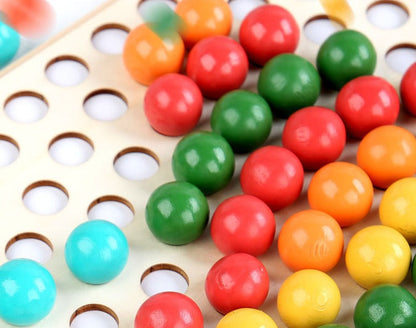 Close-up of a child's hand using tweezers to stack colorful wooden rainbow beads, boosting fine motor skills.