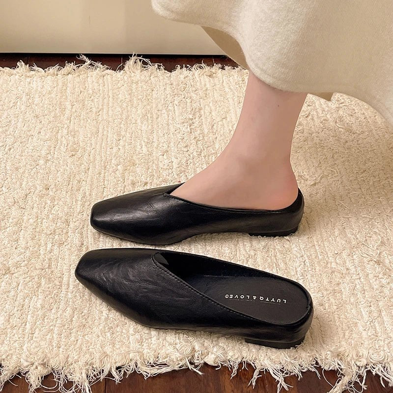 Side view of a woman wearing versatile black square toe slip-on flats, great for work or leisure.