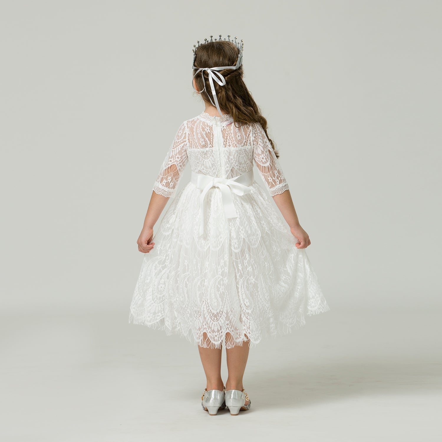 Back view of an elegant girls' lace dress featuring a decorative ribbon tie closure