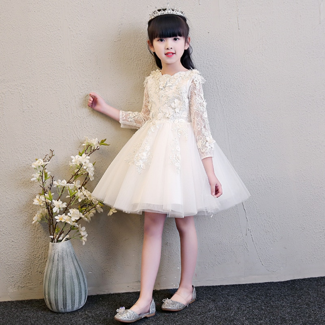 Close-up of the delicate lace and floral appliques on a girls' elegant party gown, showing detail.