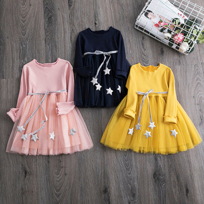 Young girl happily twirling in a stylish star mesh long sleeve party dress for toddlers.
